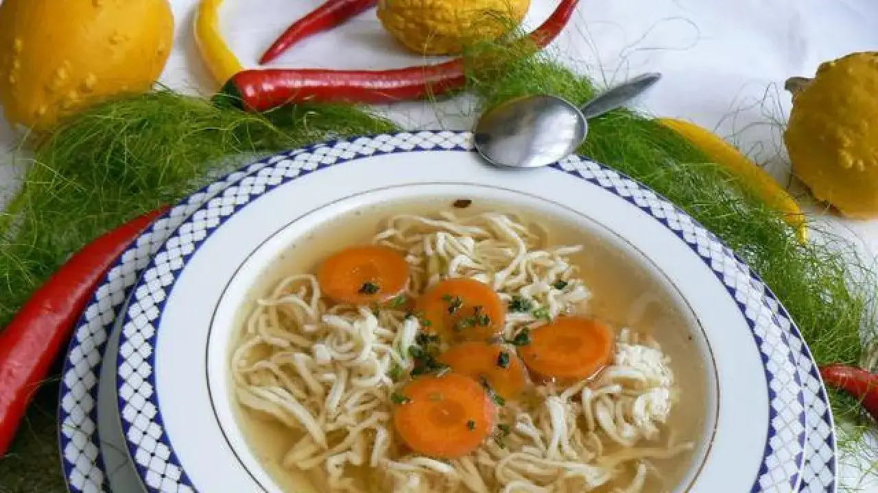 rosół z makaronem w misce, świeży lubczyk, marchewka